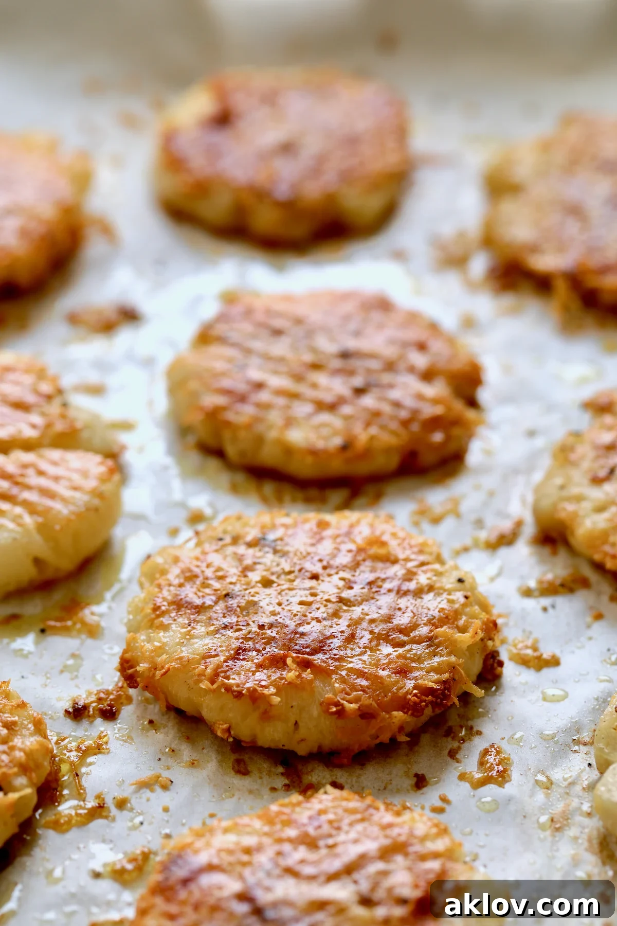 A batch of golden, crispy Parmesan Crusted Crushed Turnips cooling on parchment paper after baking, showcasing their irresistible texture.