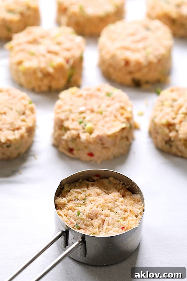 A measuring cup filled with tuna kimchi mixture, next to several perfectly formed tuna cakes on a baking sheet, ready for chilling.