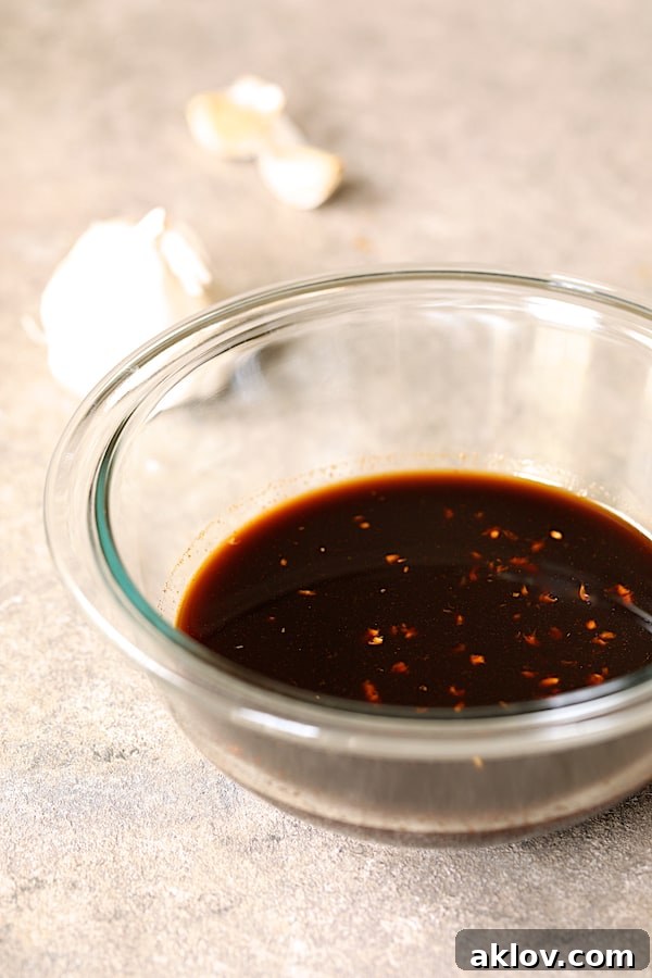 A small glass bowl filled with the vibrant Soy-Ginger dipping sauce, ready to accompany the tuna kimchi cakes.