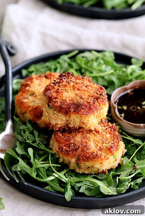 Close-up hero shot of Tuna Kimchi Cakes with Soy Ginger Dipping Sauce on plate with arugula and dipping sauce