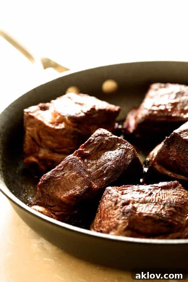 Beef short ribs being expertly browned in a hot skillet, creating a rich crust before slow cooking.