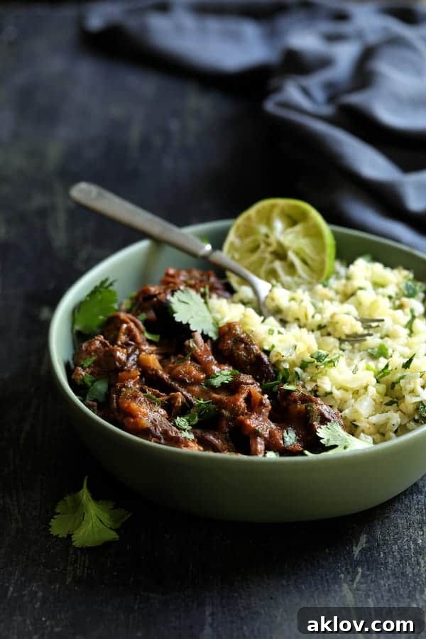 Delicious shredded Slow Cooker Beef Short Ribs Barbacoa served with Cilantro Lime Cauliflower Rice in a green bowl, garnished with cilantro and lime.