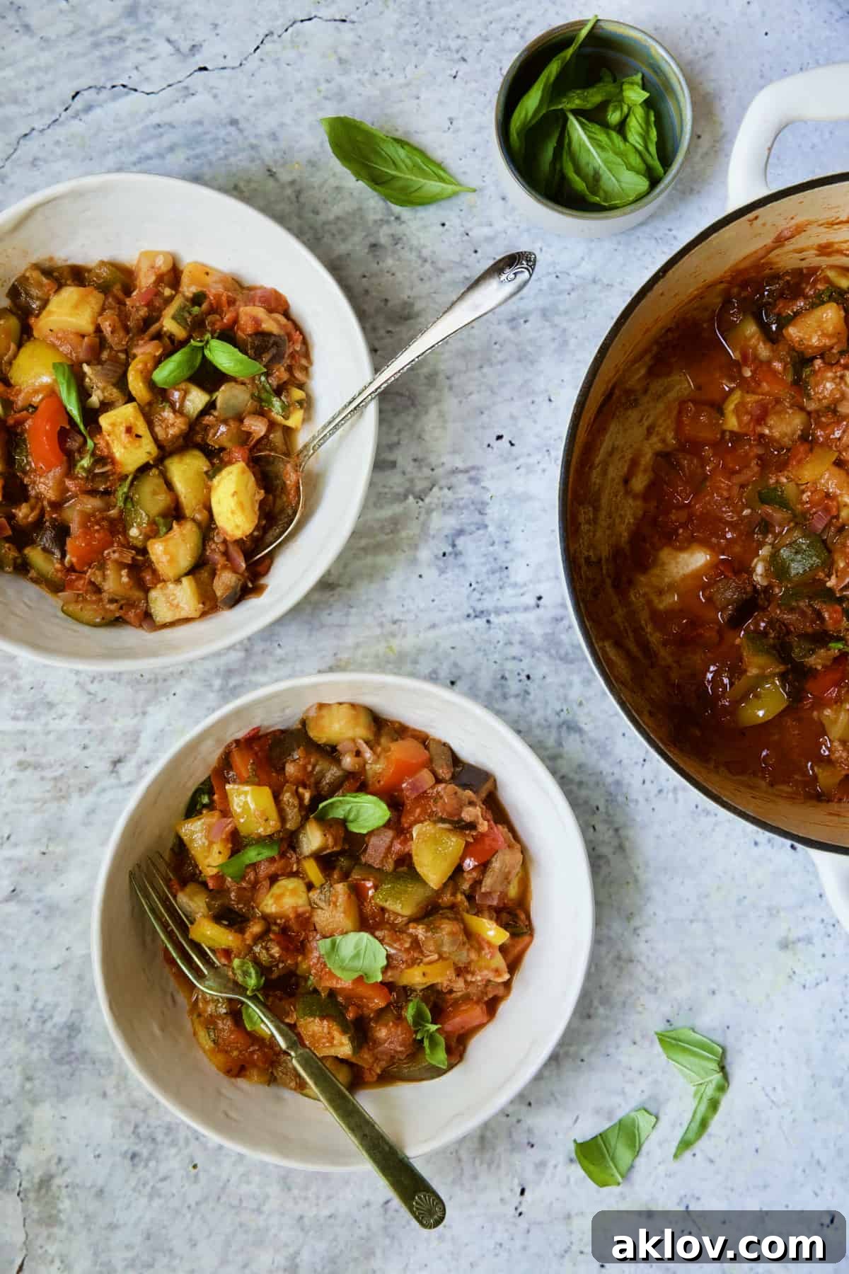 Two servings of Classic French Ratatouille in white bowls garnished with fresh basil.