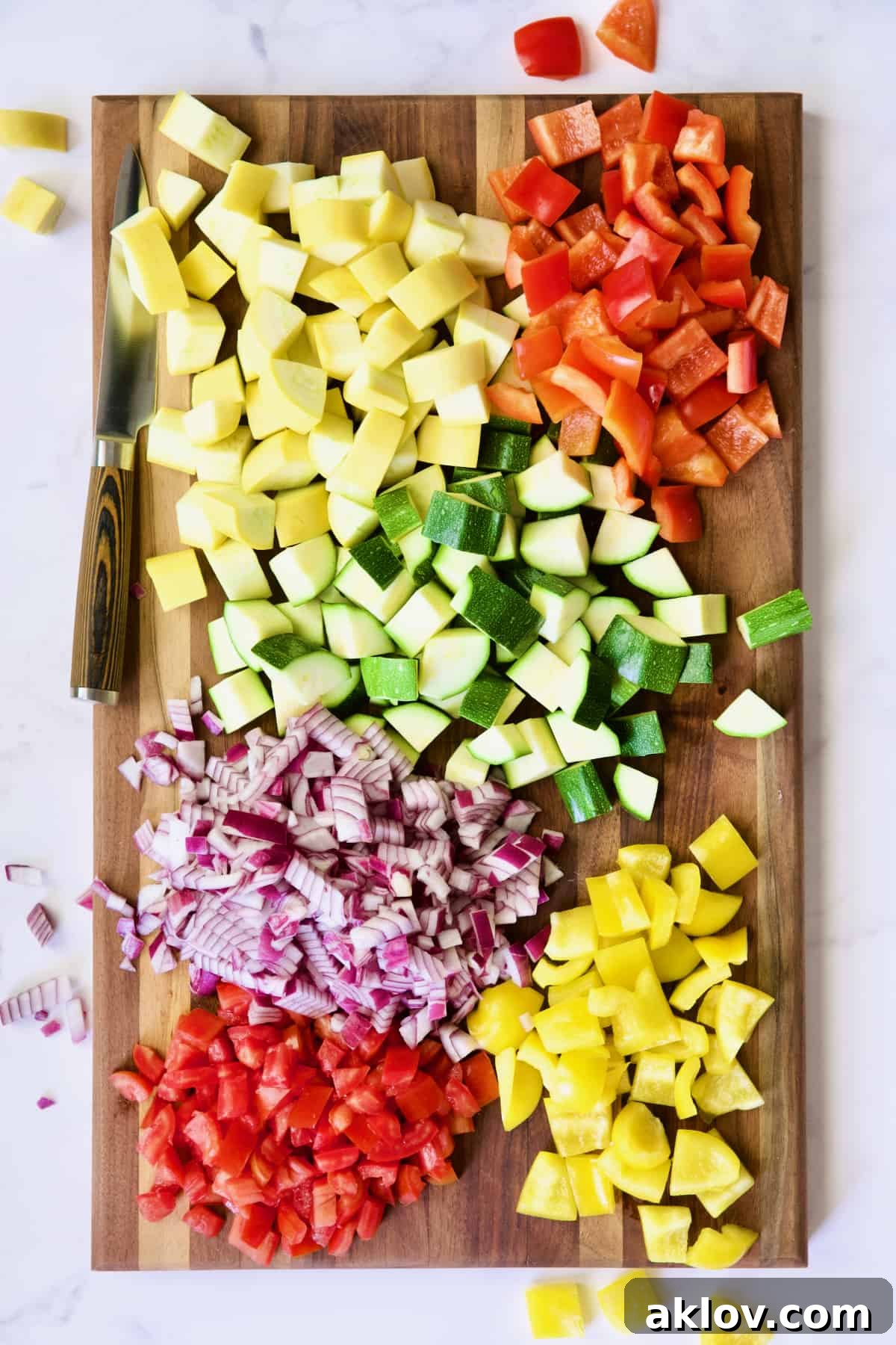 Vegetables cut up for ratatouille on dark wood cutting board.