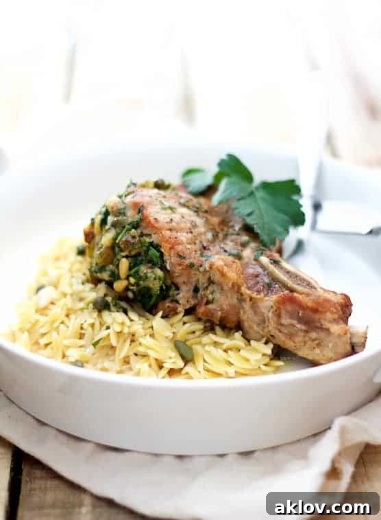 Photo of Sicilian-Stuffed Pork Chops with White Wine Caper Sauce and orzo garnished with parsley.