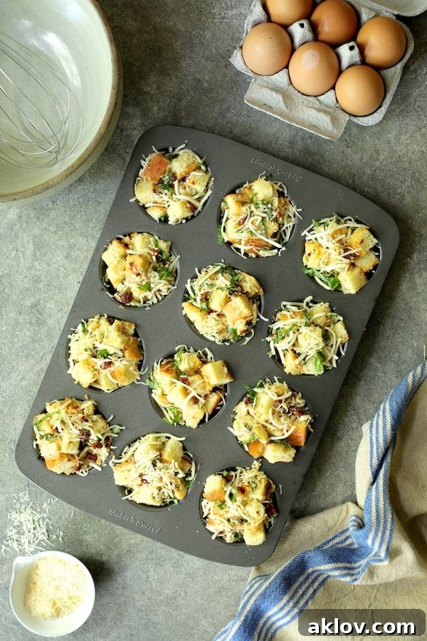 Photo of stratas in a muffin pan, filled with bread, cheese, basil, and sun-dried tomatoes, before the custard is added.