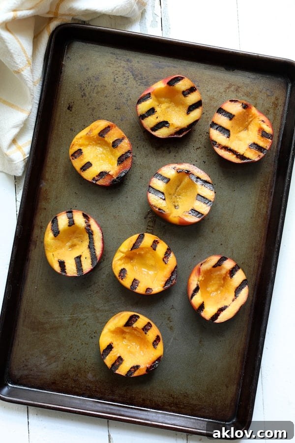 Photo of eight grilled peaches on sheet pan.