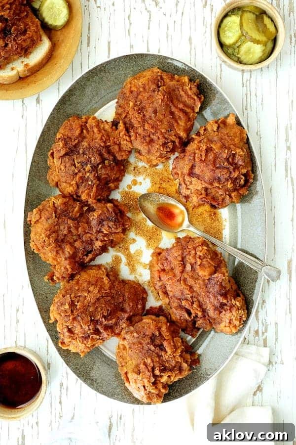 Photo of Nashville Style Hot Fried Chicken on gray rimmed platter drizzled with hot sauce. A perfect homemade Nashville Hot Chicken recipe.