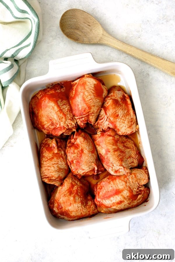 Photo of 8 raw chicken thighs in marinade in white dish ready to be battered and fried for Nashville Hot Chicken.
