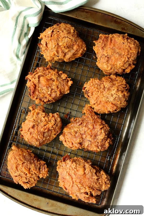 Photo of fried chicken on rack draining after being fried, ready for the Nashville Hot Chicken sauce.