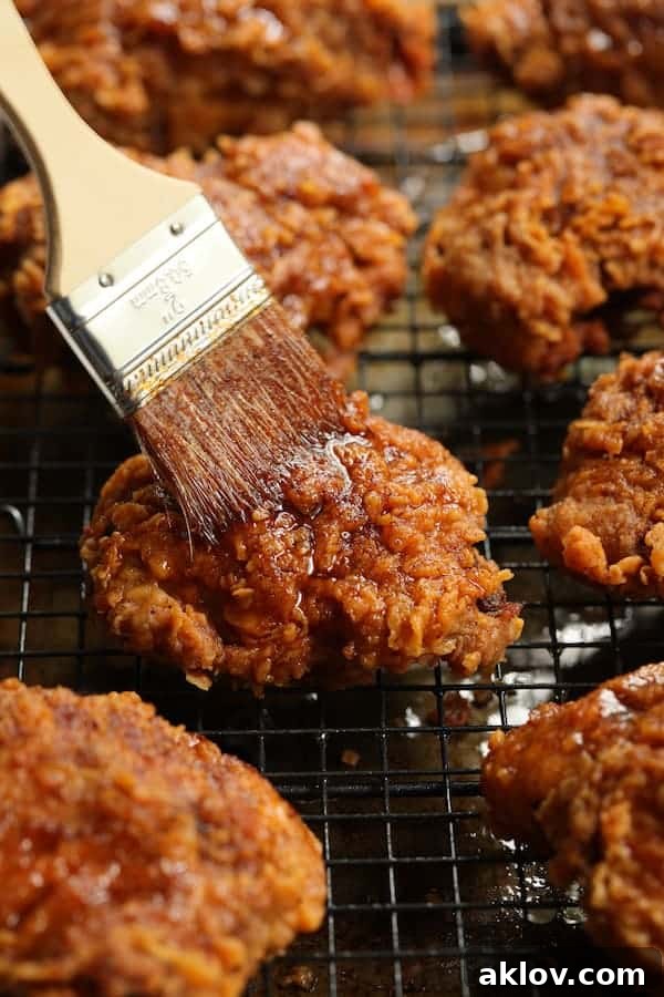 Photo of Nashville Style Hot Fried Chicken on rack being brushed with hot sauce, adding the signature spicy glaze.