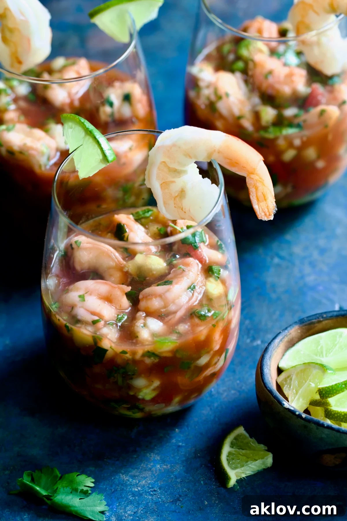 A perfectly assembled Mexican Shrimp Cocktail in a glass, elegantly garnished with a lime wedge and a whole shrimp.