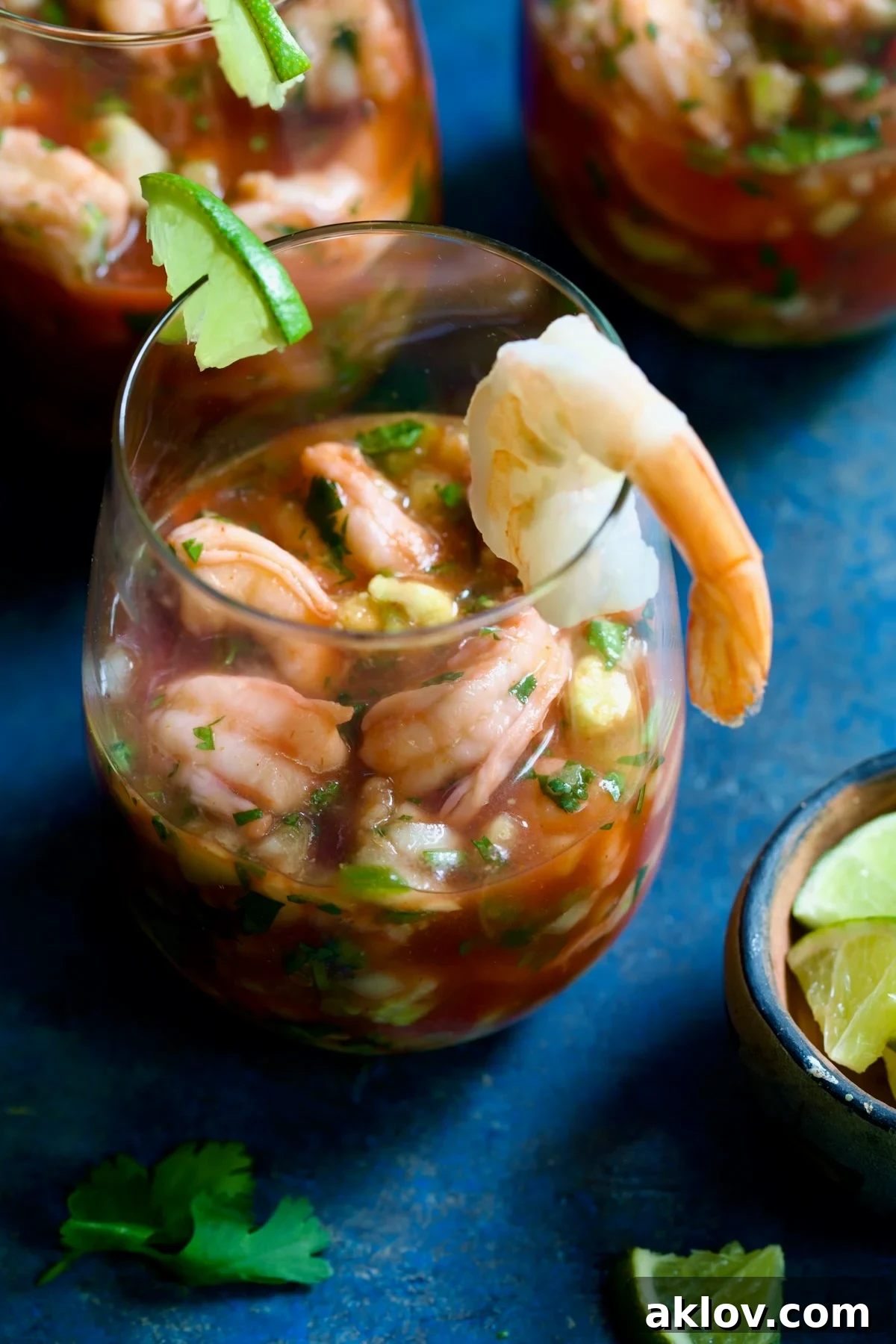 A close-up of a single glass of Mexican Shrimp Cocktail, garnished with a lime wedge and shrimp, ready to be enjoyed.