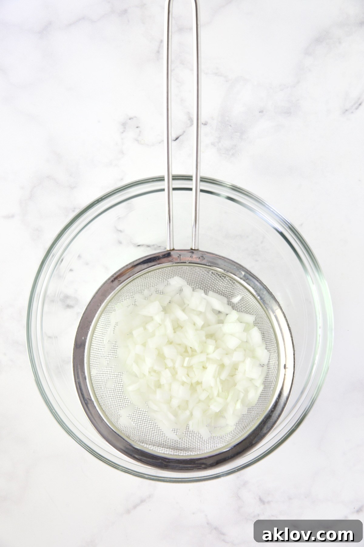 Onions in sieve set over glass bowl.
