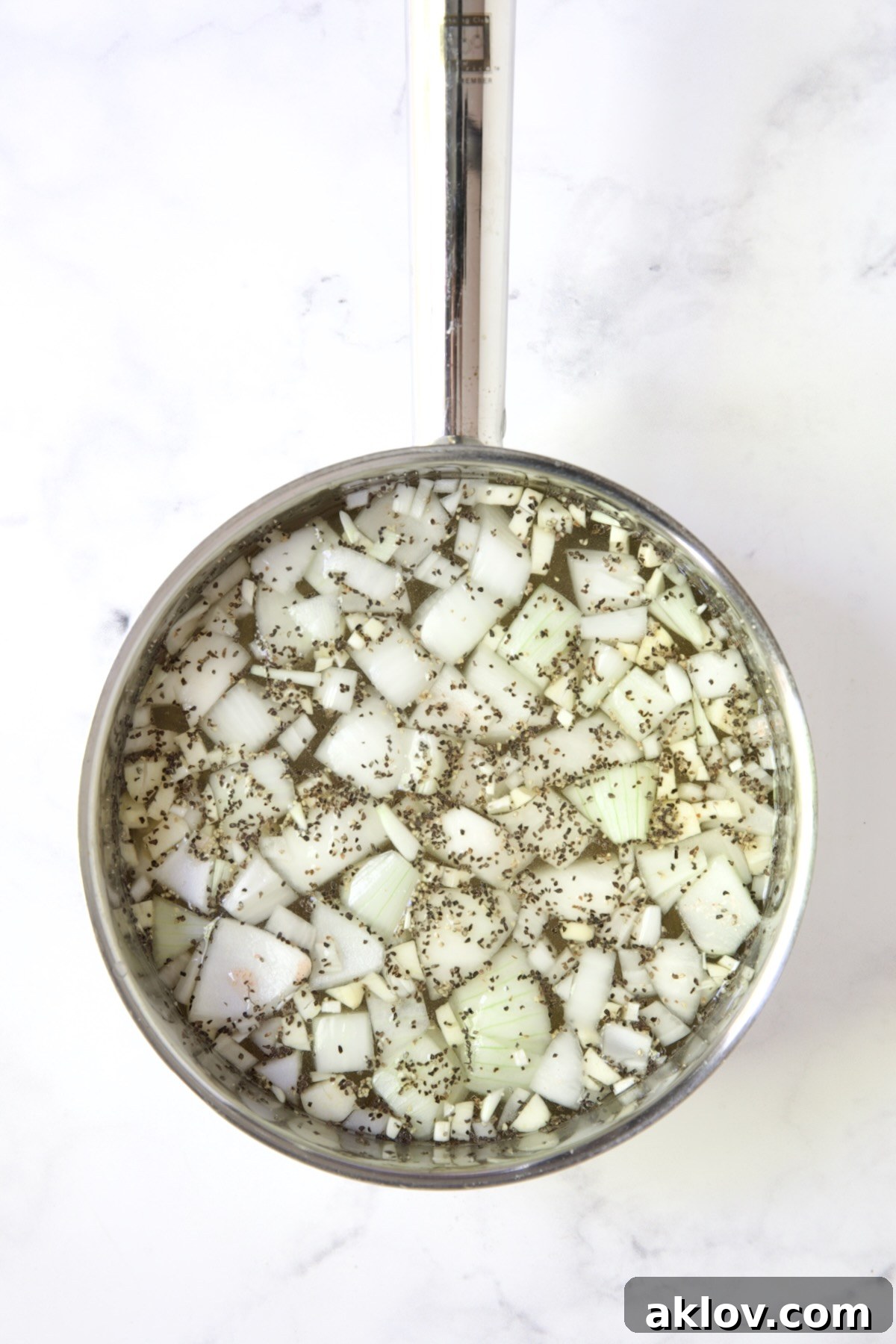 Chunks of onions, salt and pepper in stainless steel saucepan.