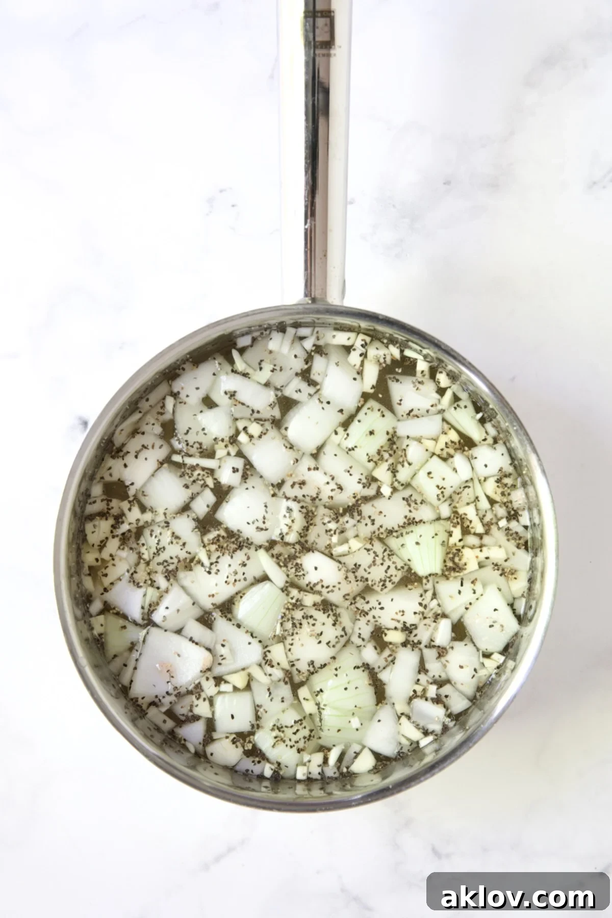 Onion chunks, garlic, salt, and pepper in a stainless steel saucepan, ready to infuse the shrimp cooking water.