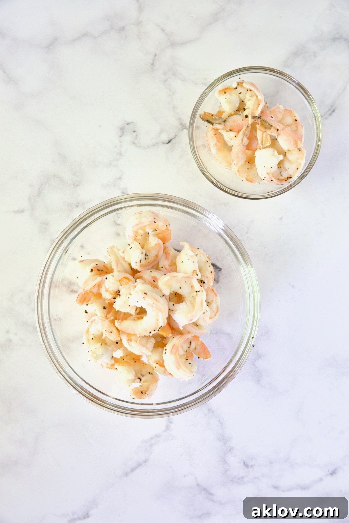Two bowls of cooked shrimp: One with tails removed and the other with tails.