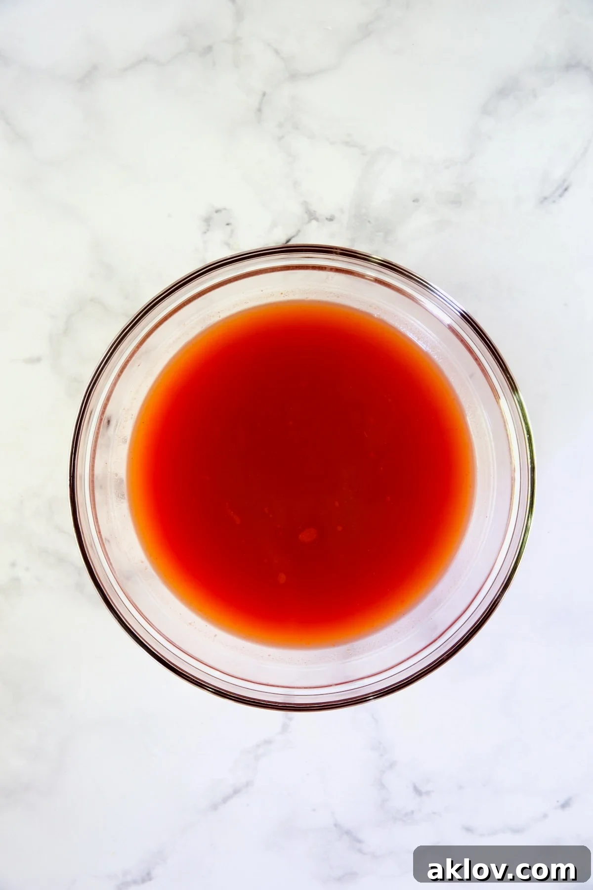 The vibrant cocktail sauce perfectly blended in a clear glass bowl, ready to be added to the shrimp and vegetables.