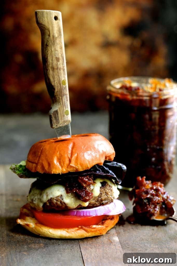 Photo of Grilled Burgers with Bacon Tomato Jam and Smoked Gouda with steak knife inserted into burger.