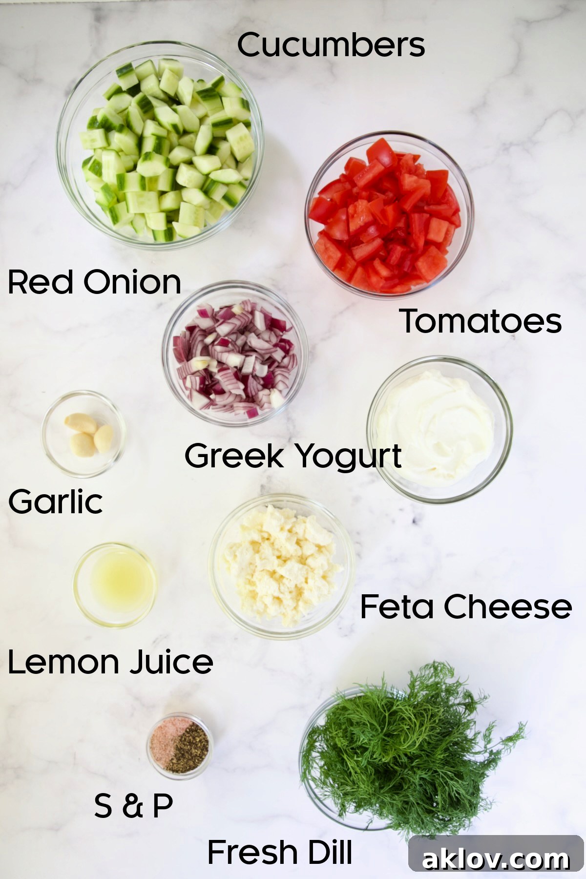 Individual fresh ingredients for Creamy Cucumber Feta Tomato Salad thoughtfully arranged and displayed in separate clear glass bowls, ready for preparation and mixing.