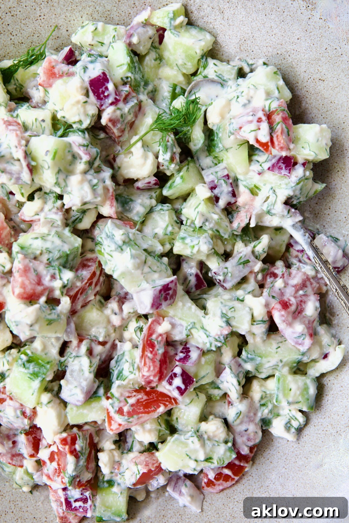 The vibrant Creamy Cucumber Feta Tomato Salad, perfectly mixed and glistening with dressing, ready to be served and enjoyed, highlighting its fresh and inviting appeal.