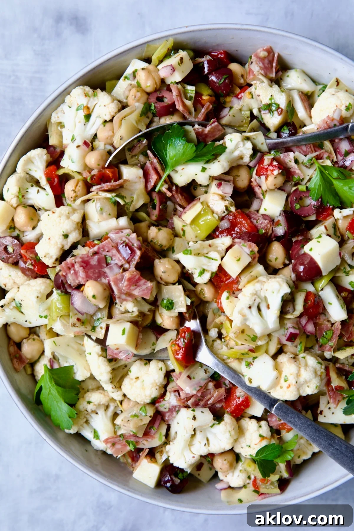 Vibrant Cauliflower Antipasto Salad in a rustic serving bowl, garnished with fresh herbs and ready to be served at a summer gathering.