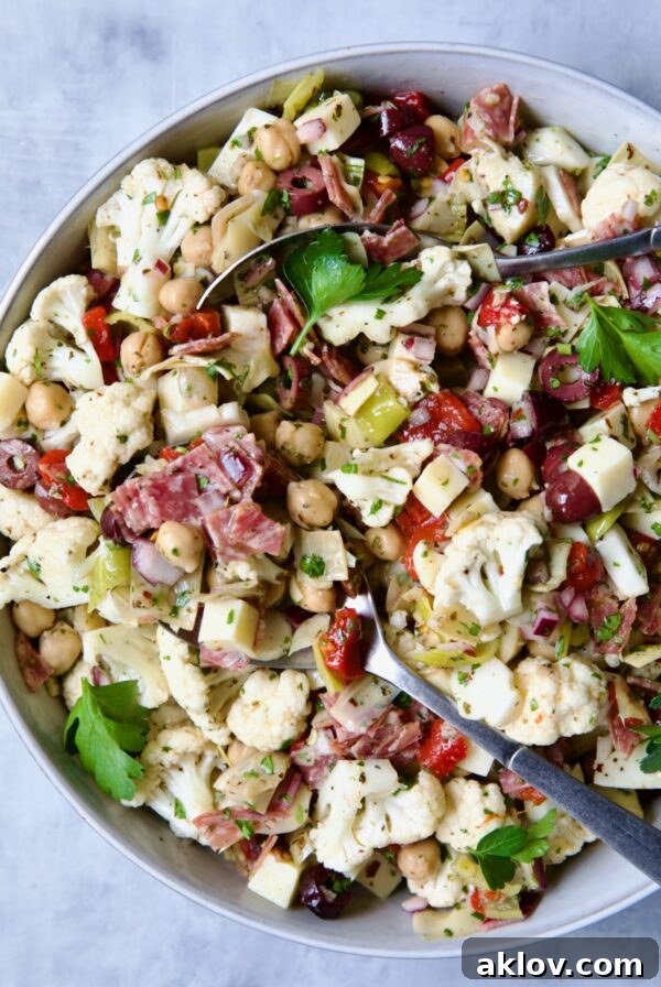 Cauliflower Antipasto Salad in serving bowl with serving utensils.