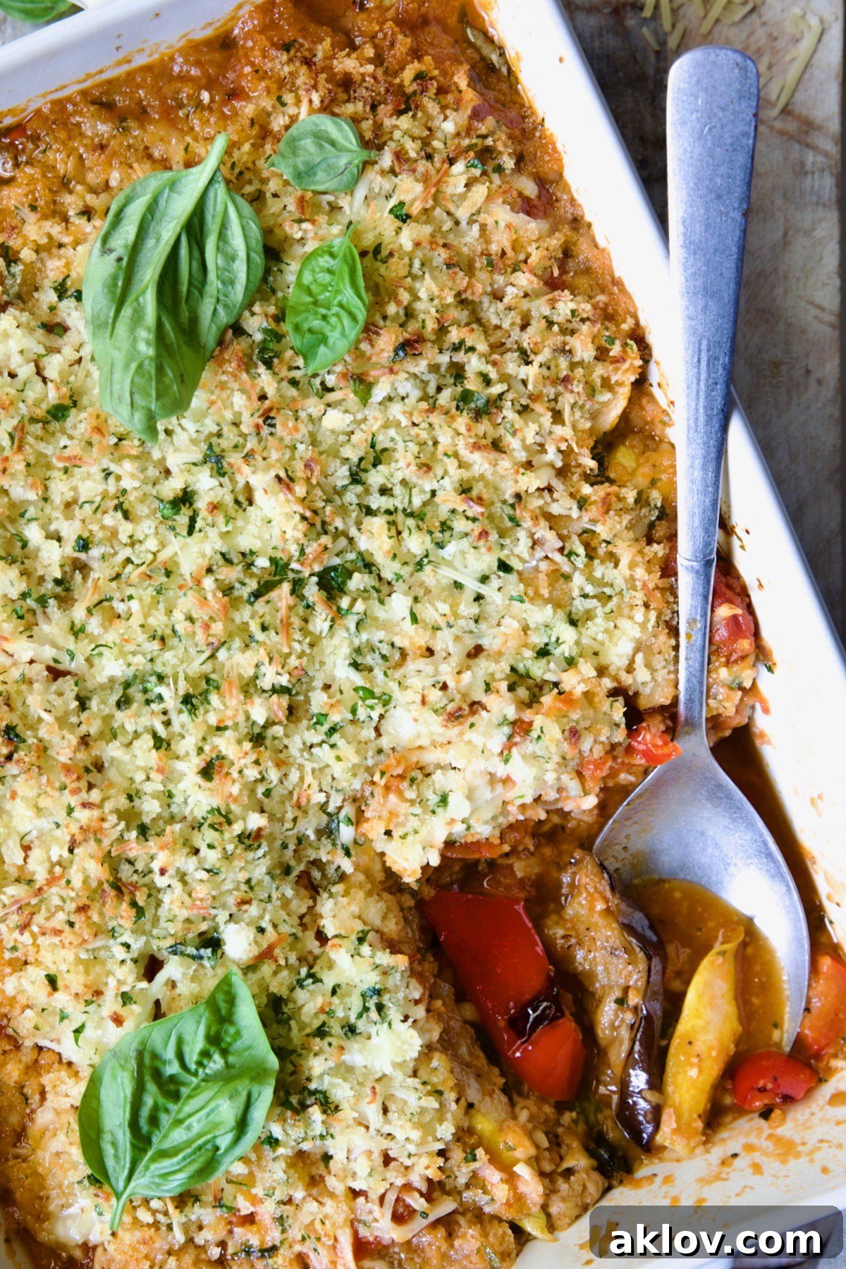 Summer Vegetable Parmigiana in white baking dish with serving spoon scooping some up.