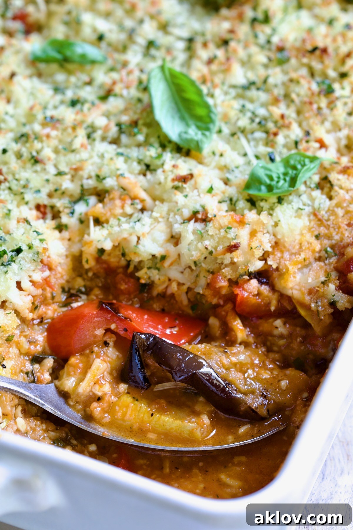 Summer Vegetable Parmigiana in white baking dish with serving spoon scooping some up.