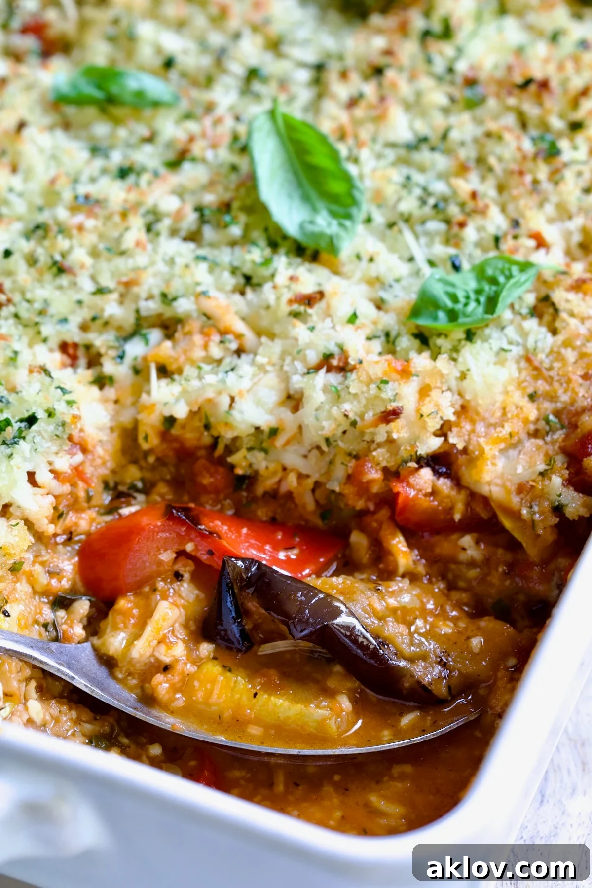 A close-up shot of a single serving of Summer Vegetable Parmigiana, expertly scooped from the baking dish, highlighting the tender layers of vegetables, molten cheese, and savory sauce.