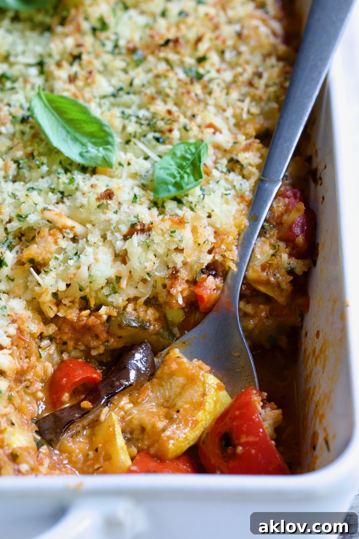 Summer Vegetable Parmigiana in white baking dish with serving spoon scooping some up.