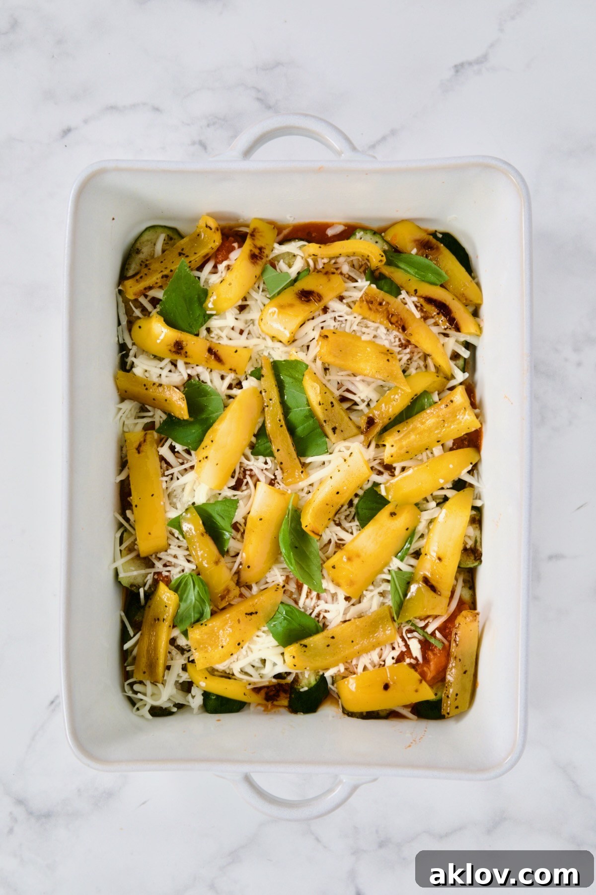 Layer of yellow bell pepper in white rectangular baking dish.