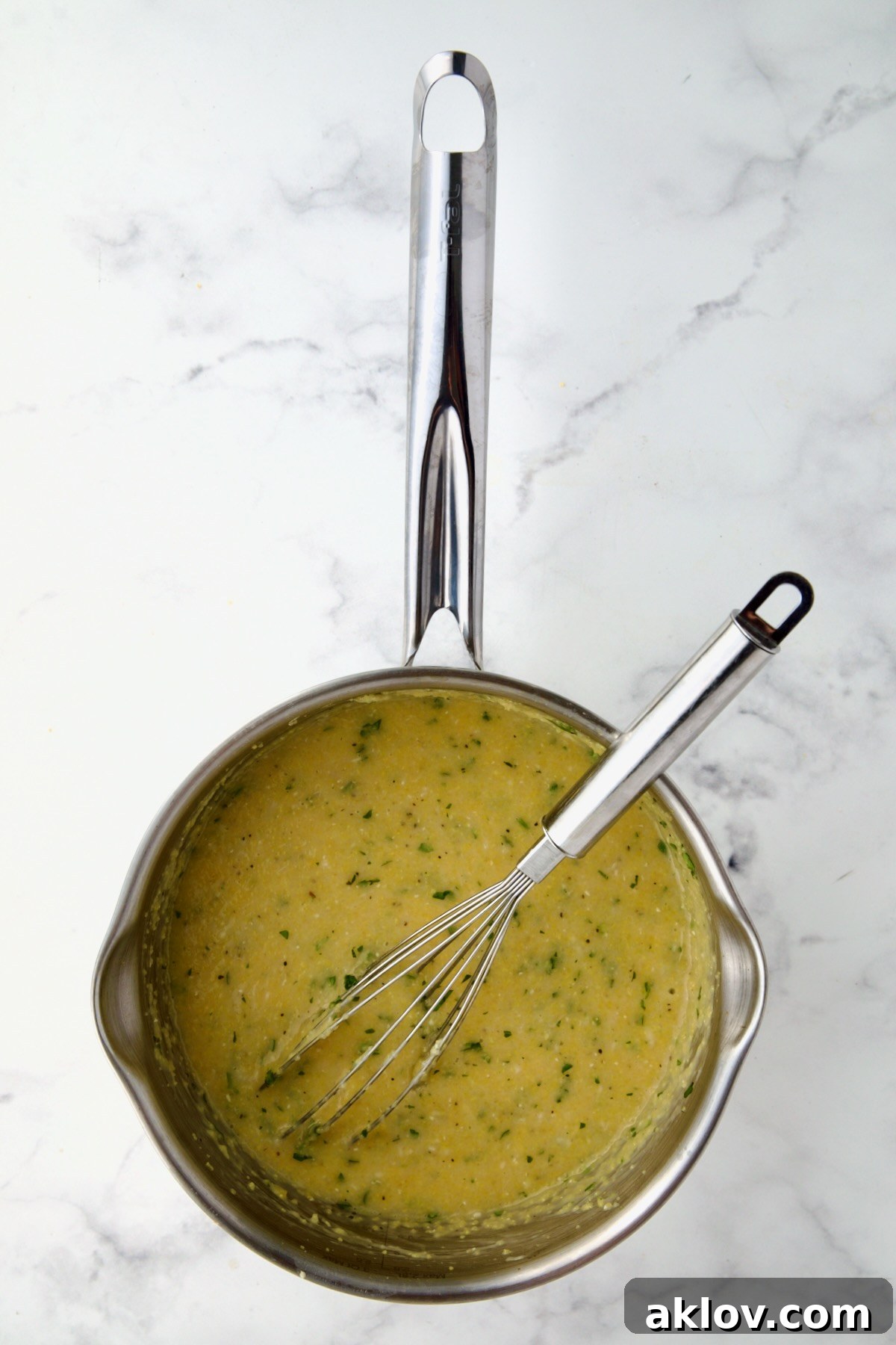 Polenta in stainless steel saucepan with wire whisk.