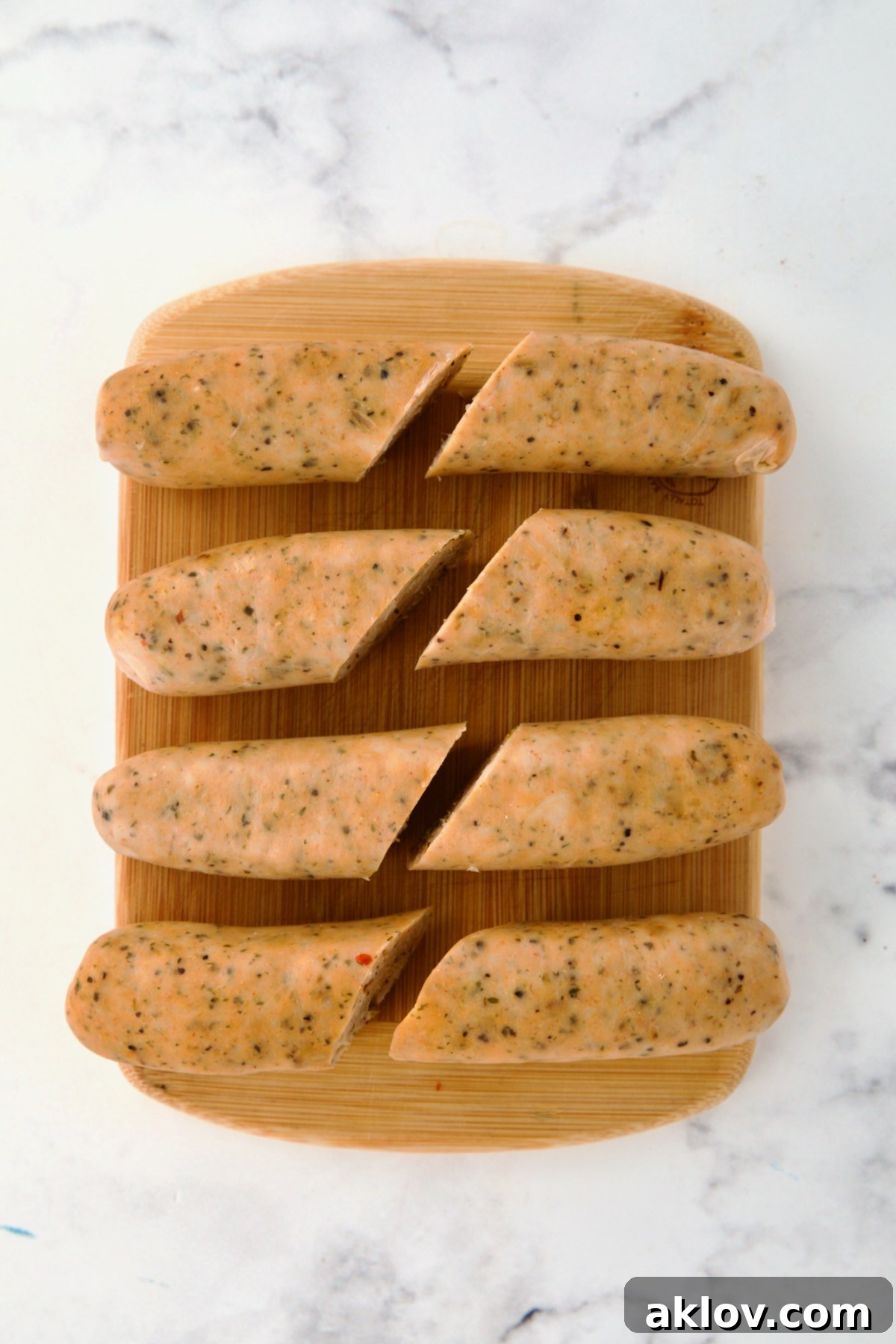 Four links of chicken sausage on bamboo cutting board cut in half for eight pieces.