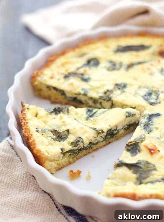 Photo of Spinach and Feta Quiche with Quinoa Crust in white baking dish with focus on one slice.