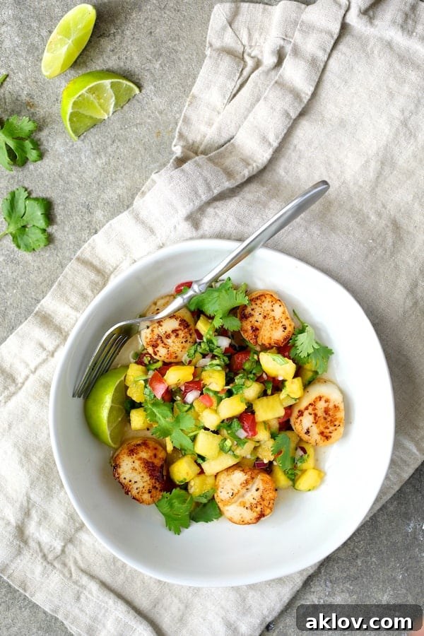 Perfectly Pan-Seared Sea Scallops with Fresh Watermelon Tomato Salsa, garnished with cilantro and lime wedges in a pristine white bowl.