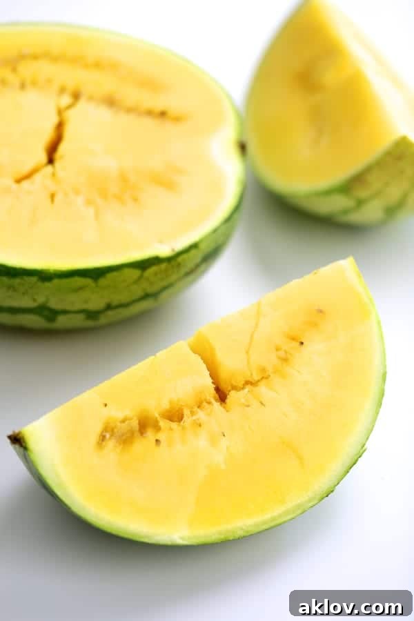 Close-up photo of a vibrant yellow watermelon, cut into large, juicy pieces, showcasing its unique color and texture.