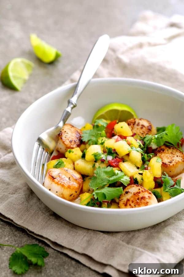 Artfully plated Pan-Seared Sea Scallops with Watermelon Tomato Salsa, served in a white bowl on a beige linen napkin, garnished with fresh cilantro and lime wedges.