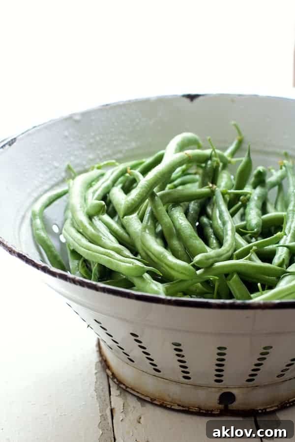 Freshly washed and trimmed green beans in a white colander, ready for skillet charring.