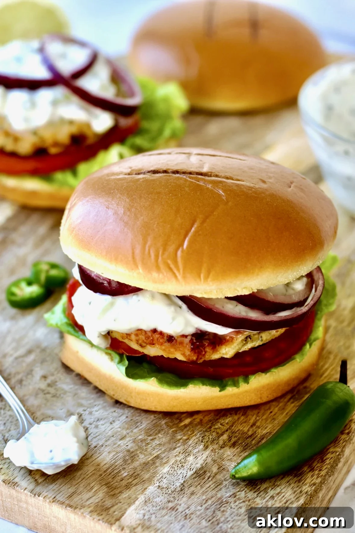 A close-up shot of Ground Chicken Burgers with Spicy Tzatziki beautifully arranged on a wooden cutting board, highlighting their texture and presentation.