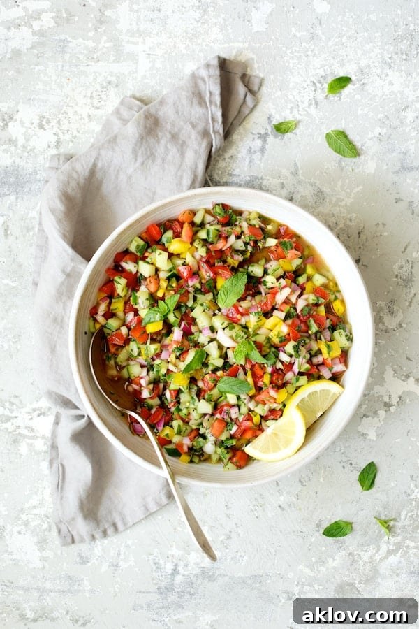 Close-up of Middle Eastern Chopped Salad served in a white bowl, set against a grey background with a matching napkin and lemon accents.