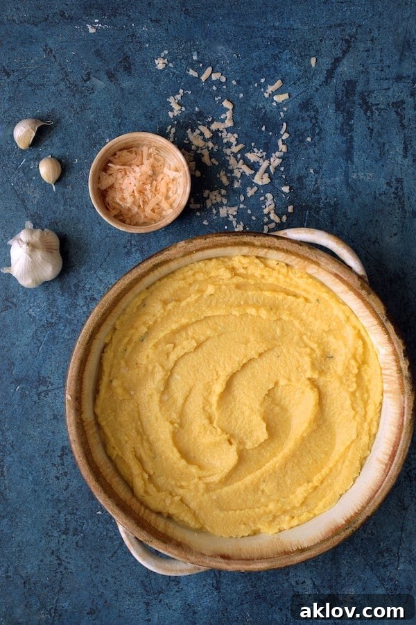 A close-up photo of the polenta layer cooling and setting in a round earthenware baking dish on a blue background, ready for the next delicious layers.