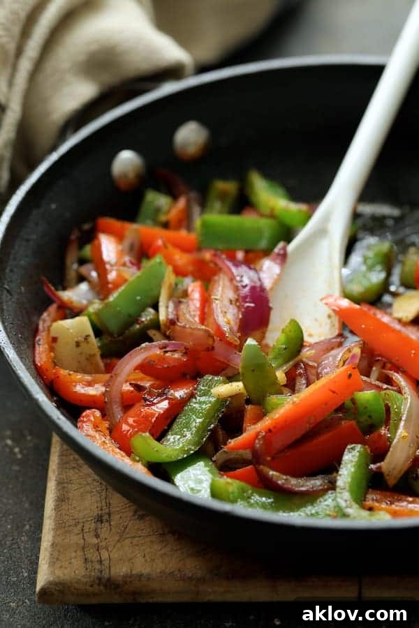 A vibrant photo of cooked onions and colorful bell peppers in a skillet, soft yet retaining a slight bite.