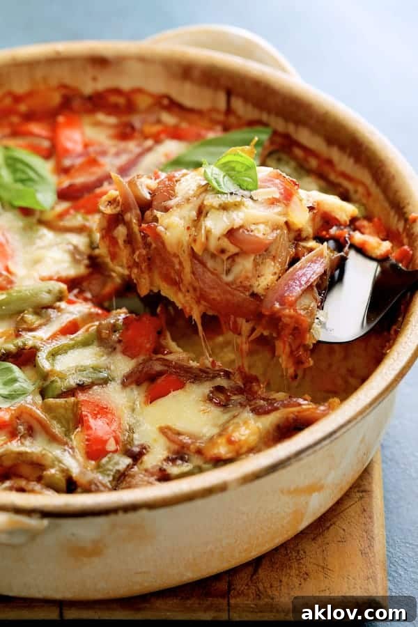 A close-up photo of a server pulling a cheesy, savory spoonful of Italian Sausage and Bell Pepper Polenta Bake from the dish, highlighting its gooey texture.