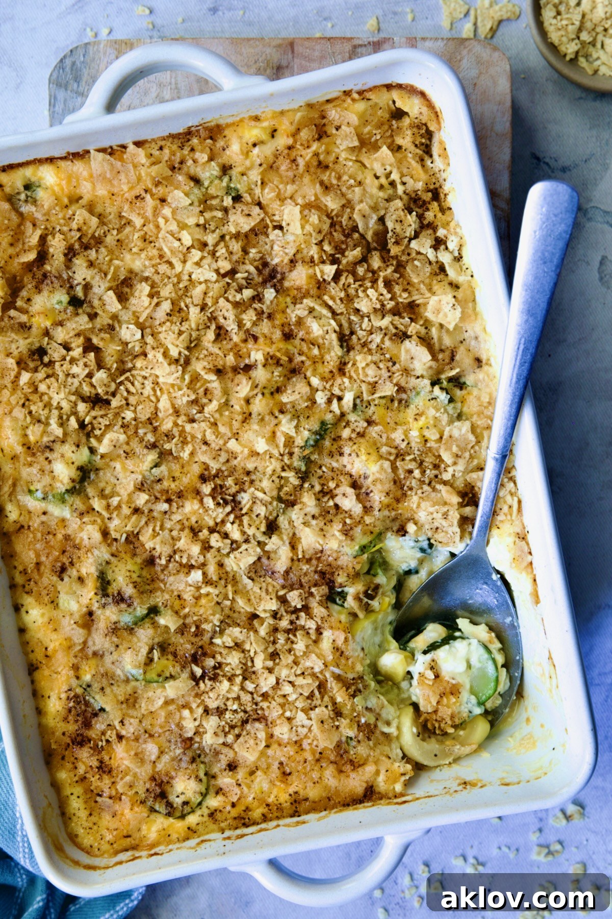 Serving a portion of Summer Squash Corn Poblano Casserole from a rectangular white baking dish.