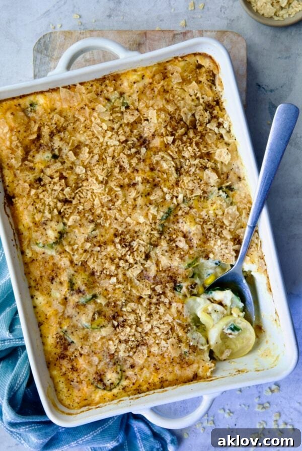 Summer Squash Corn Poblano Casserole in rectangular white baking dish with serving spoon.