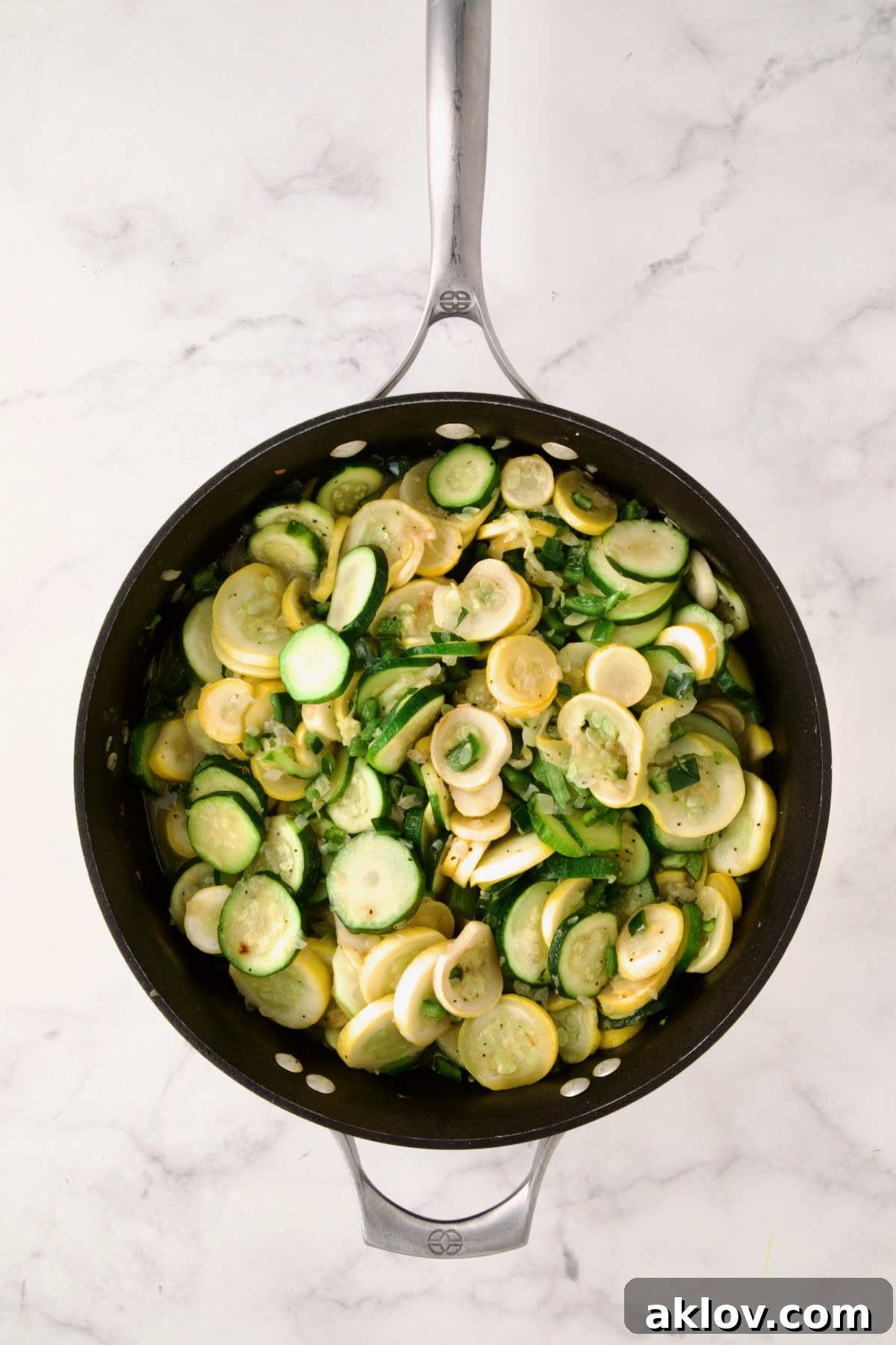 Cooked zucchini, yellow squash, and poblano peppers in a nonstick skillet, showing a slight char and tenderness.