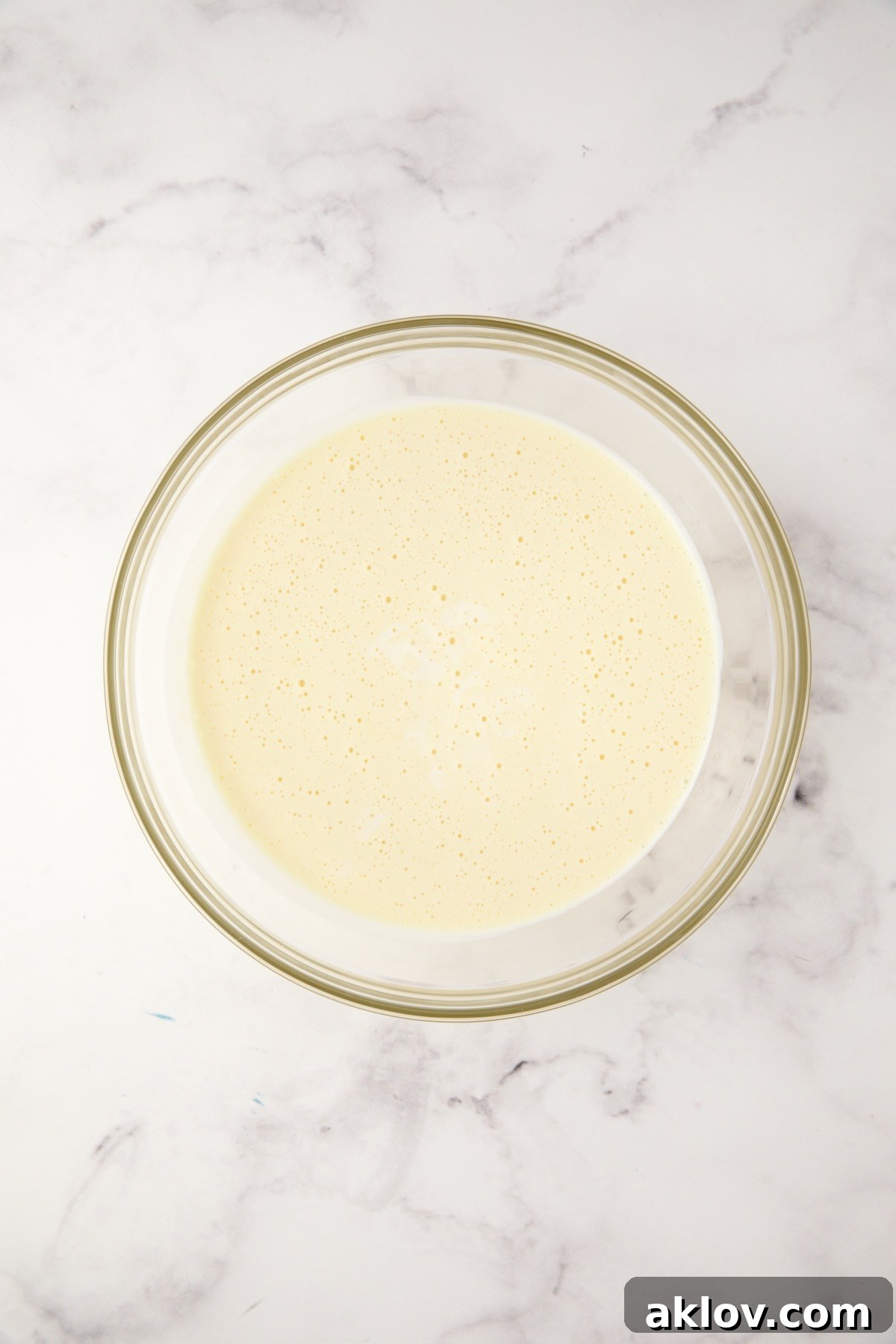 A creamy custard blend of cream cheese, mayonnaise, half-and-half, and eggs in a glass bowl.