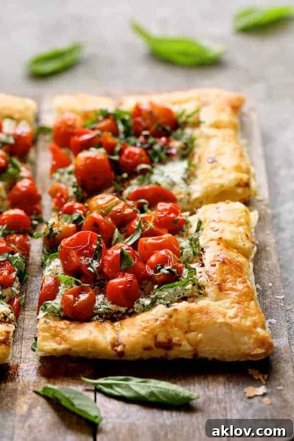 Photo of Roasted Cherry Tomato Tart with Herbed Ricotta on a wooden surface, garnished with fresh basil leaves. The tart is golden brown with vibrant red tomatoes and green herbs.