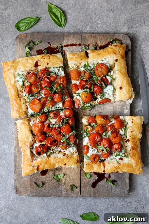 Photo of a fully assembled Roasted Cherry Tomato Tart with Herbed Ricotta on a wooden cutting board, perfectly cut into four neat pieces, ready to be served.